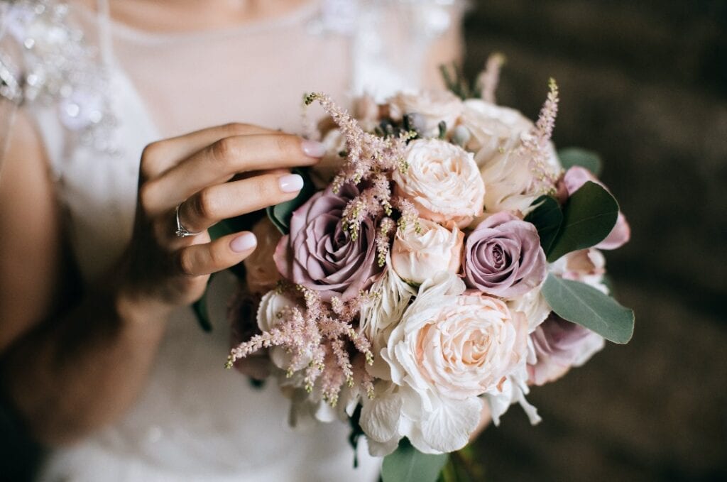 The bride holds a beautiful wedding bouquet of pink and white flowers in her hands